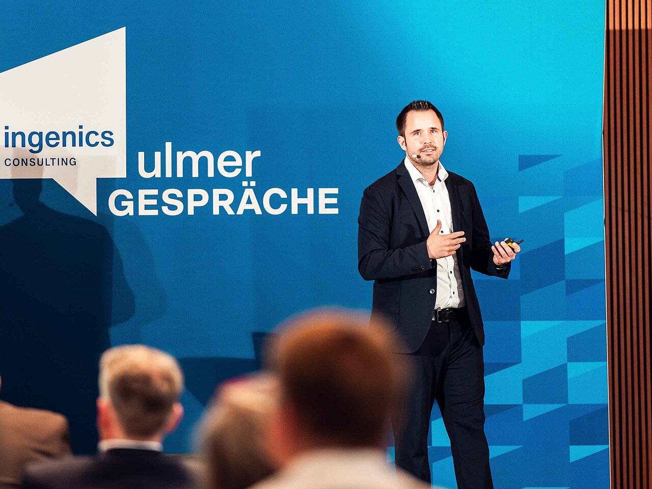 Referierende Person hält einen Vortrag auf der Bühne der Ulmer Gespräche vor einer Präsentationswand